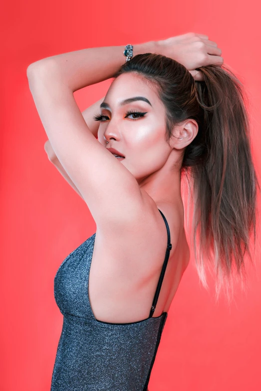 a woman posing in front of a red background, by Robbie Trevino, trending on pexels, beautiful asian girl, girl silver ponytail hair, posing in bra, on a gray background