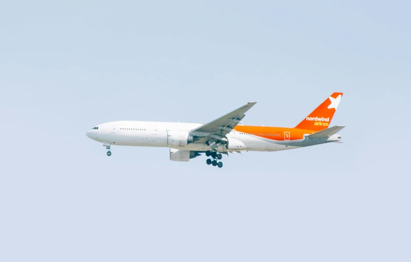 a large jetliner flying through a blue sky, by Lorraine Fox, pexels contest winner, bauhaus, orange color, large tail, aoshima, springtime