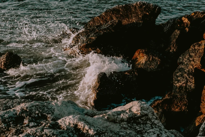 a man riding a surfboard on top of a rocky beach, an album cover, pexels contest winner, water particles, charybdis, brown, youtube thumbnail