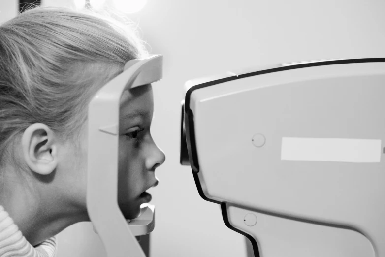 a black and white photo of a little girl getting her eye examined, by Adam Marczyński, computer vision, animation, concept photo