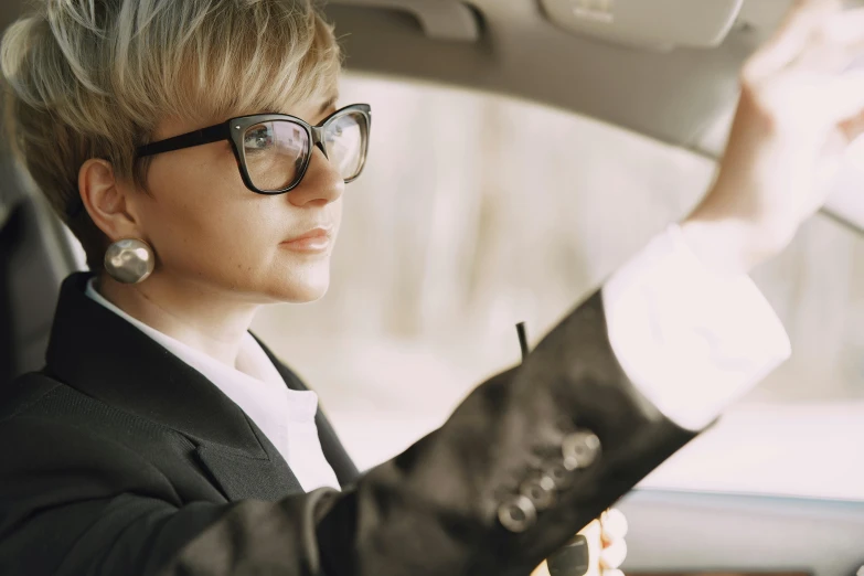 a woman sitting in the driver's seat of a car, trending on pexels, androgyny, wearing black rimmed glasses, avatar image, blond