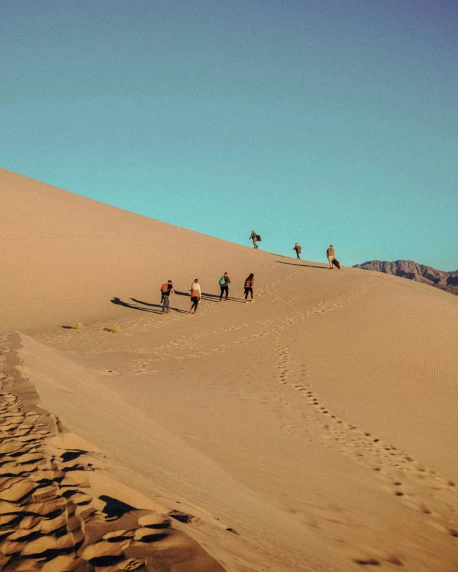 a group of people walking up a sand dune, instagram post, climbing, death vally, sandy colors