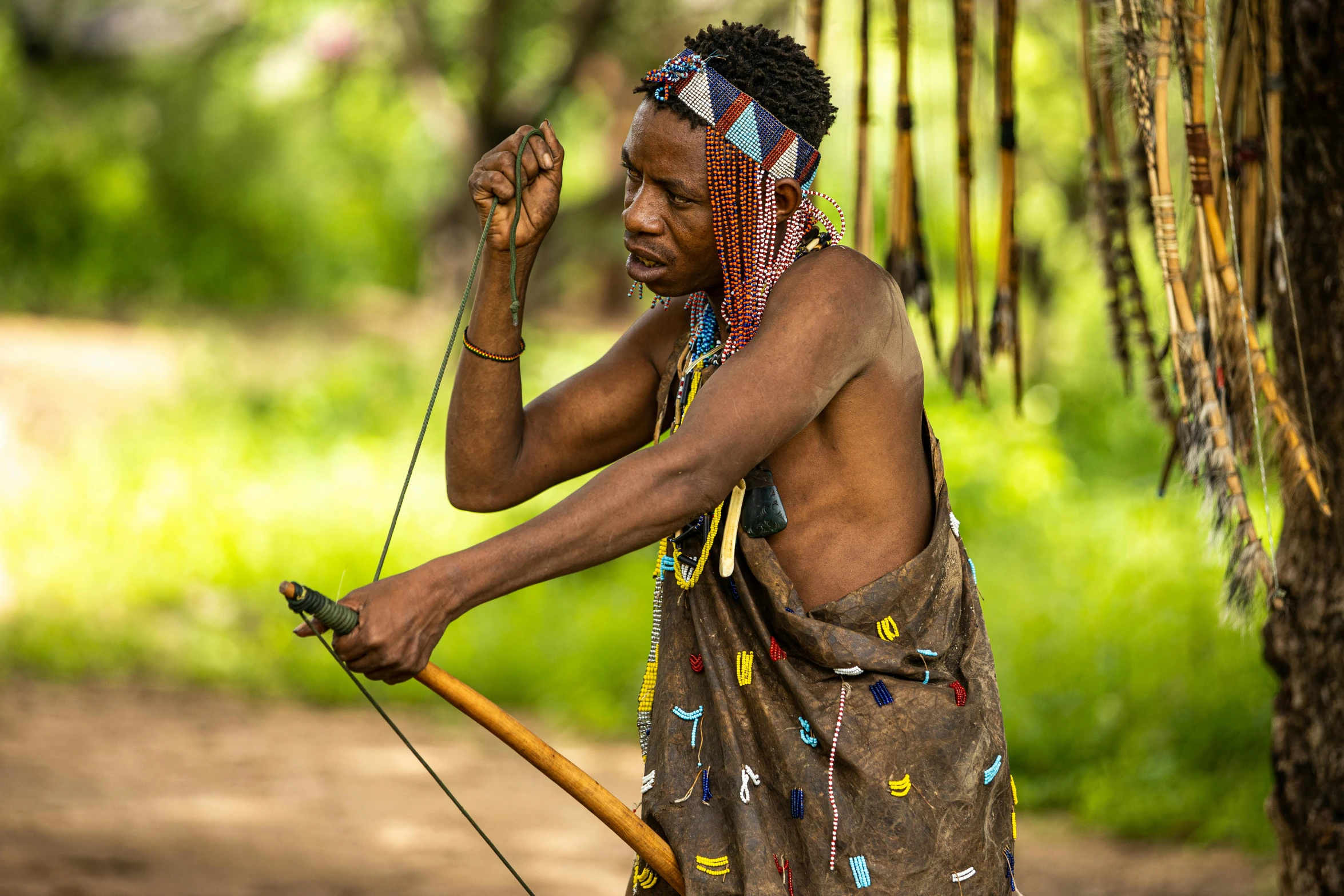 a man that is holding a bow and arrow, by Dietmar Damerau, pexels contest winner, hurufiyya, intricate african jewellery, lush surroundings, avatar image, three - quarter view