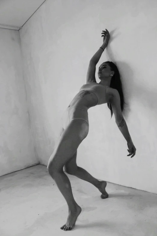 a black and white photo of a woman leaning against a wall, a statue, inspired by Vanessa Beecroft, arabesque, video still, sensual dancing, low quality photograph, 'white background'!!!