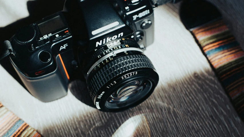 a camera sitting on top of a bed next to a pillow, by Niko Henrichon, unsplash contest winner, photorealism, photo - realistic nikon 3 5 mm, 8 0 s camera, looking down on the camera, macro lens product photo