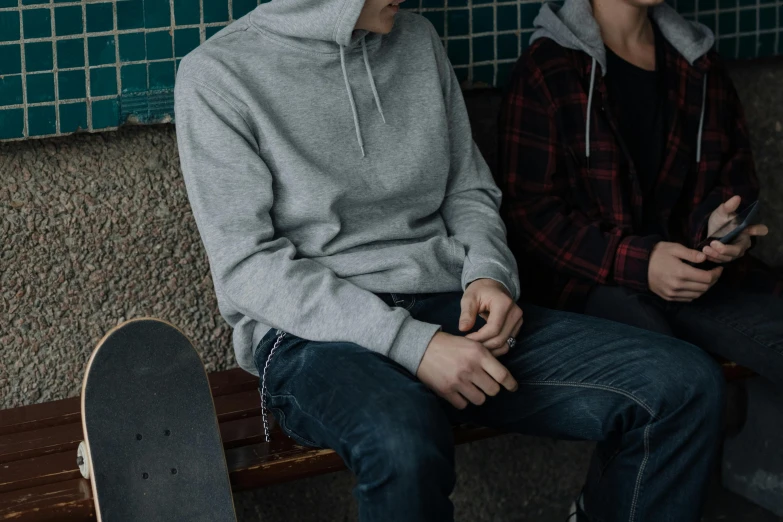 a couple of men sitting next to each other on a bench, inspired by Seb McKinnon, trending on pexels, grey hoodie, teenage boy, federation clothing, full product shot