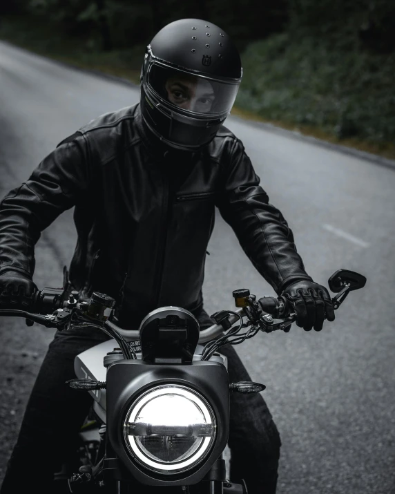 a man riding on the back of a motorcycle down a road, dark helmet, wearing a plug suit, black on black, scrambler