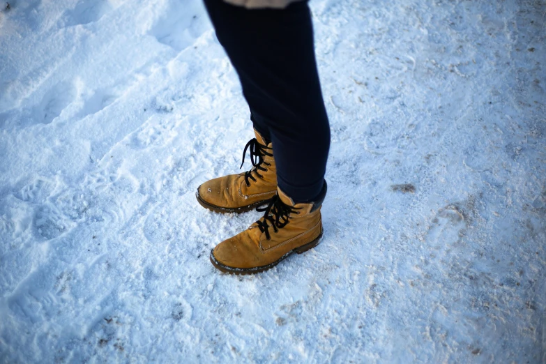a person standing in the snow wearing brown boots, a portrait, pexels, visual art, hyperdetailed, ocher details, ice seracs, schools