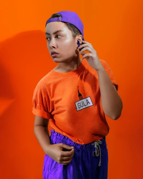 a young boy talking on a cell phone, by Julia Pishtar, wearing an orange t shirt, e-girl, ((purple)), official product photo