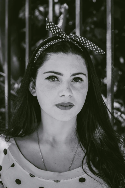 a black and white photo of a woman with a polka dot headband, a black and white photo, pexels contest winner, portait of haifa wehbe, scarlett hooft, young southern woman, desaturated