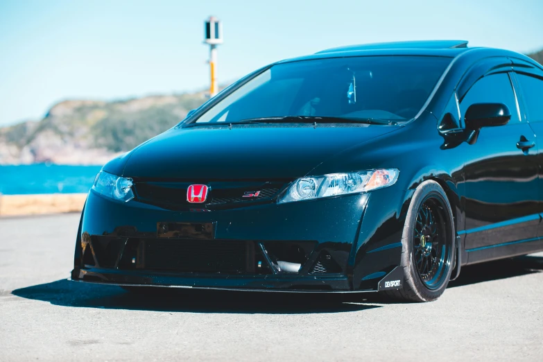 a black car parked in front of a body of water, inspired by Hiroshi Honda, unsplash, honda civic, long front end, modified, color”