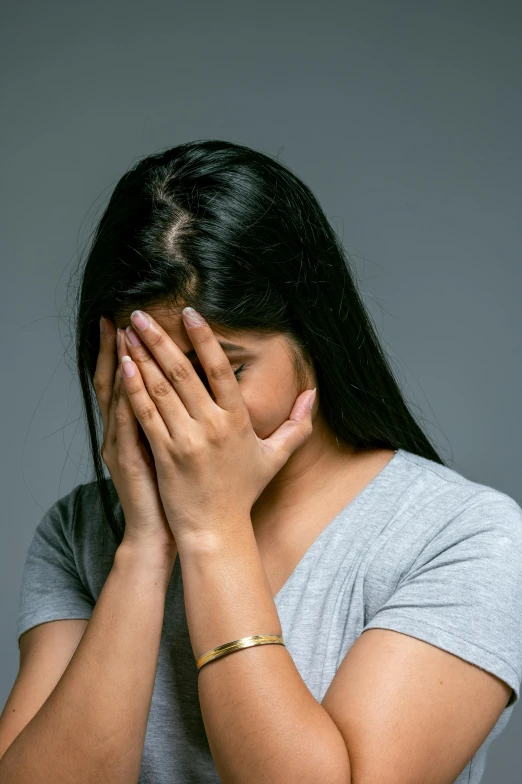 a woman covers her face with her hands, shutterstock, with depressive feeling, plain background, heartbroken, asian woman