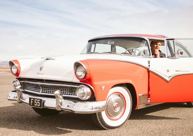 a man sitting in the driver's seat of a red and white car, by Joe Bowler, unsplash, square, retro 5 0 s style, gordon onslow ford, pink