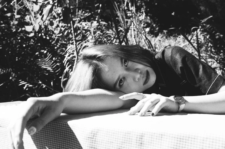 a black and white photo of a woman laying on a bench, portrait of jossi of blackpink, picnic, hand on her chin, on a white table