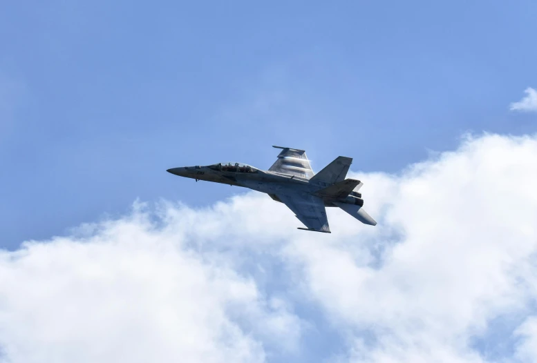 a fighter jet flying through a cloudy blue sky, pexels contest winner, photorealism, fa-18 hornet, concert, grey, may)