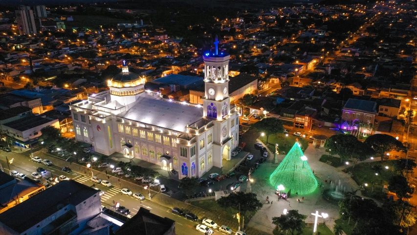 a large white building with a green christmas tree in front of it, by Luis Miranda, pexels contest winner, photographic isometric cathedral, shipibo, night time footage, square