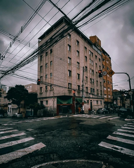 a large building sitting on the side of a road, inspired by Elsa Bleda, unsplash contest winner, quito school, telephone wires, japanese downtown, low quality photo, postapocalyptic vibes