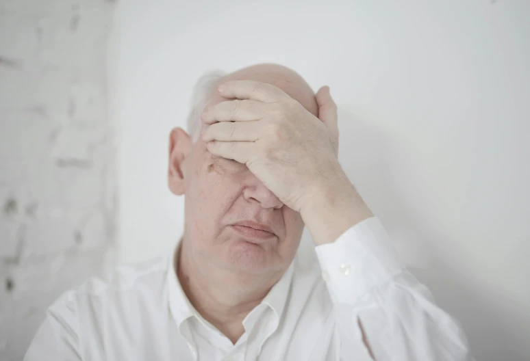 a man holding his head in his hands, pexels contest winner, grumpy [ old ], on a pale background, profile image, large forehead