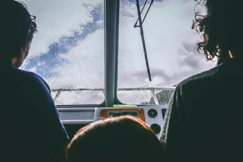 a couple of people that are looking out a window, bus, head straight down, during a storm, photo taken from a boat
