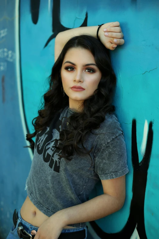 a woman leaning against a graffiti covered wall, a portrait, by Winona Nelson, pexels, dreamy mila kunis, sunny leone, square, 21 years old
