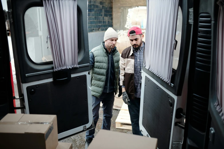 a couple of men standing inside of a van, profile image, cardboard, comforting, production still