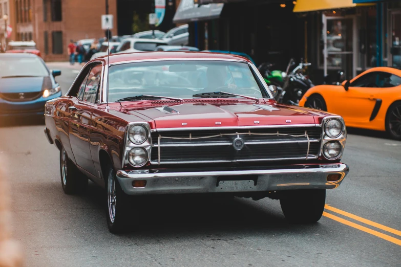 a red car driving down a city street, pexels contest winner, photorealism, ford, maroon metallic accents, 70s photo, well preserved