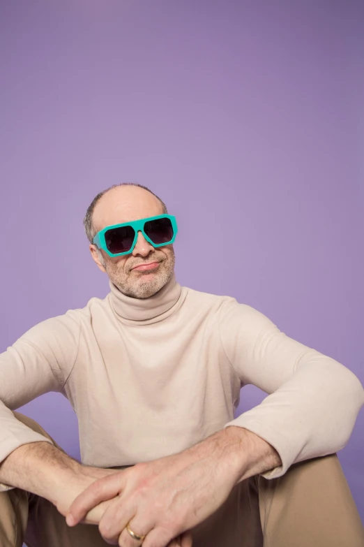 a man sitting on the ground wearing sunglasses, inspired by Leo Leuppi, trending on pexels, green and purple studio lighting, joan cornella, bald patch, smirking deviously