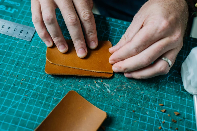 a person working on a piece of leather, unsplash, arts and crafts movement, square shapes, no - text no - logo, instruction, 3 colour