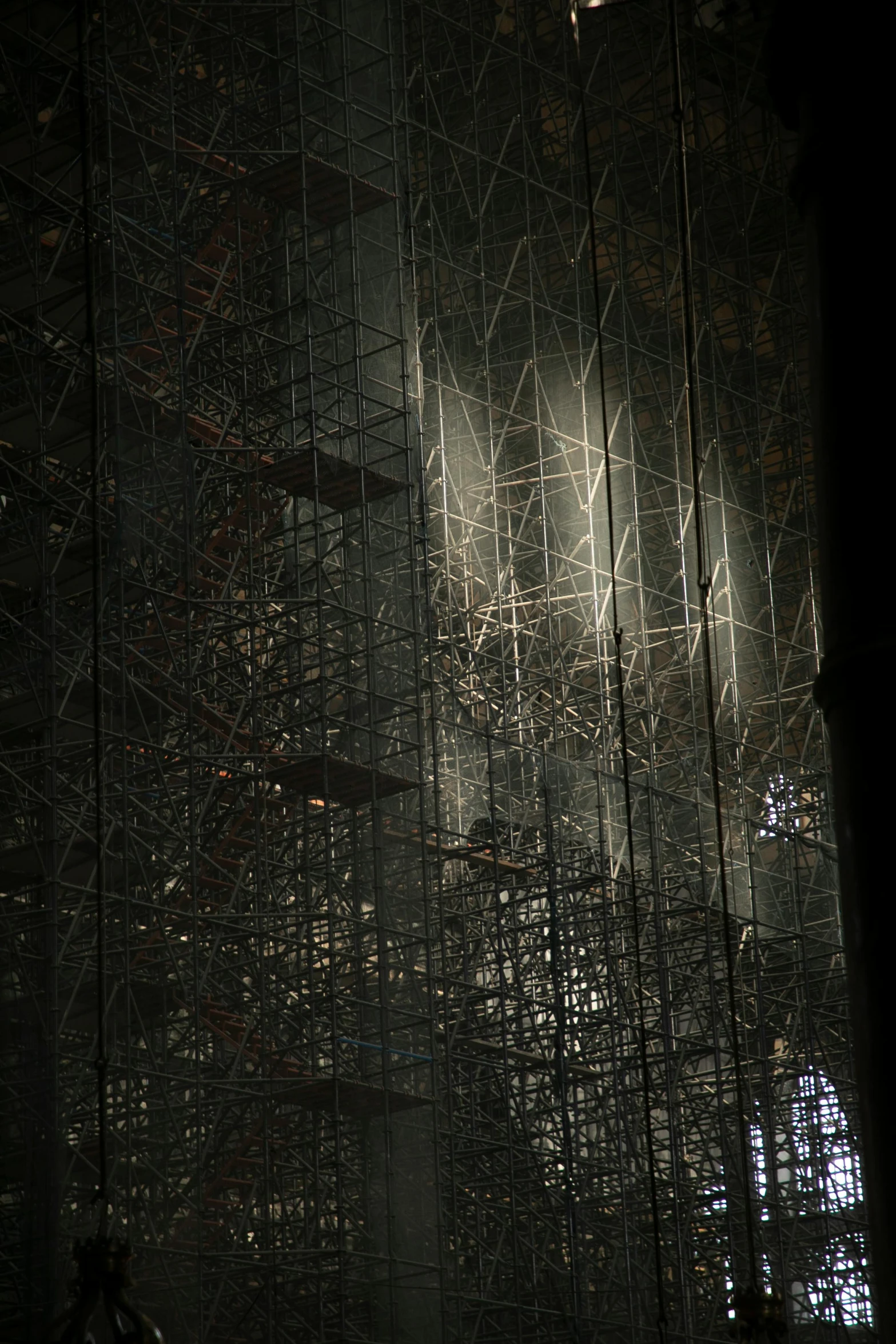 a very tall building with a lot of scaffolding, inspired by Ryoji Ikeda, light and space, inside cathedral, particle reflections, dark warehouse, up-close