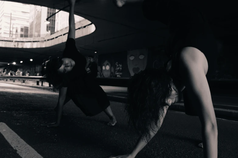 a black and white photo of a woman doing a handstand, a black and white photo, unsplash, graffiti, goth people dancing, yoga, woman holding another woman, with instagram filters