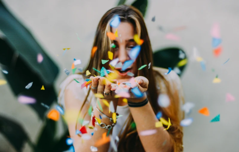 a woman holding confetti in front of her face, pexels contest winner, happening, background image, avatar image, middle close up composition, paper