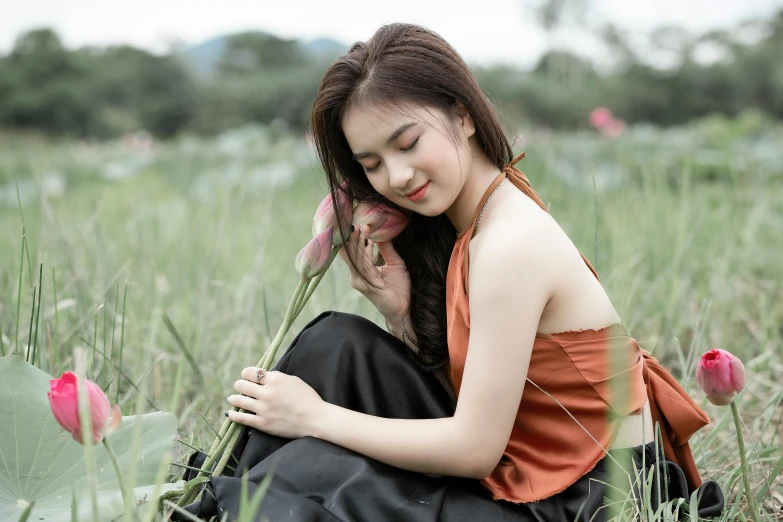 a woman sitting in a field holding a flower, by Tan Ting-pho, trending on pexels, wearing a camisole, avatar image, elegant look, high quality image