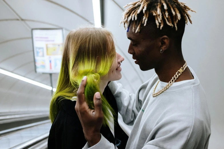 a man and a woman standing next to each other, trending on pexels, visual art, bright green hair, diverse haircuts, reaching out to each other, a girl with blonde hair