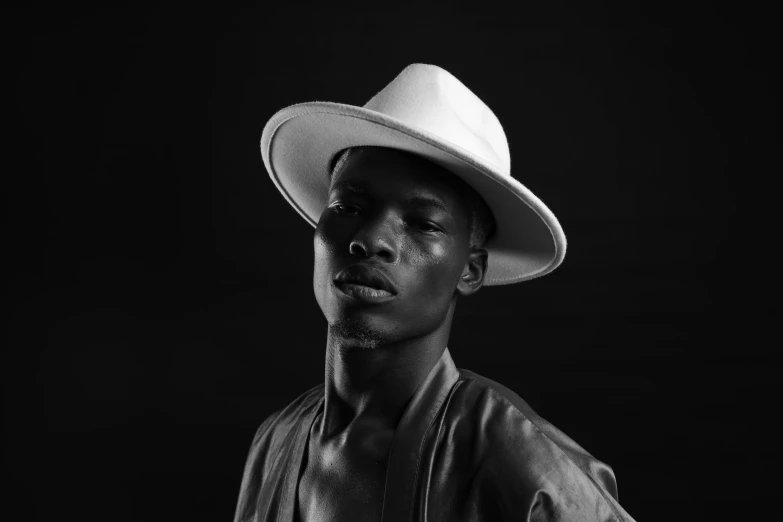 a black and white photo of a man wearing a hat, by Ottó Baditz, pexels, afrofuturism, delicate androgynous prince, adut akech, white cowboy hat, portrait lighting