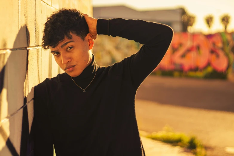 a young man leaning against a wall with his hand on his head, pexels contest winner, non binary model, (golden hour), mixed race, simon lee