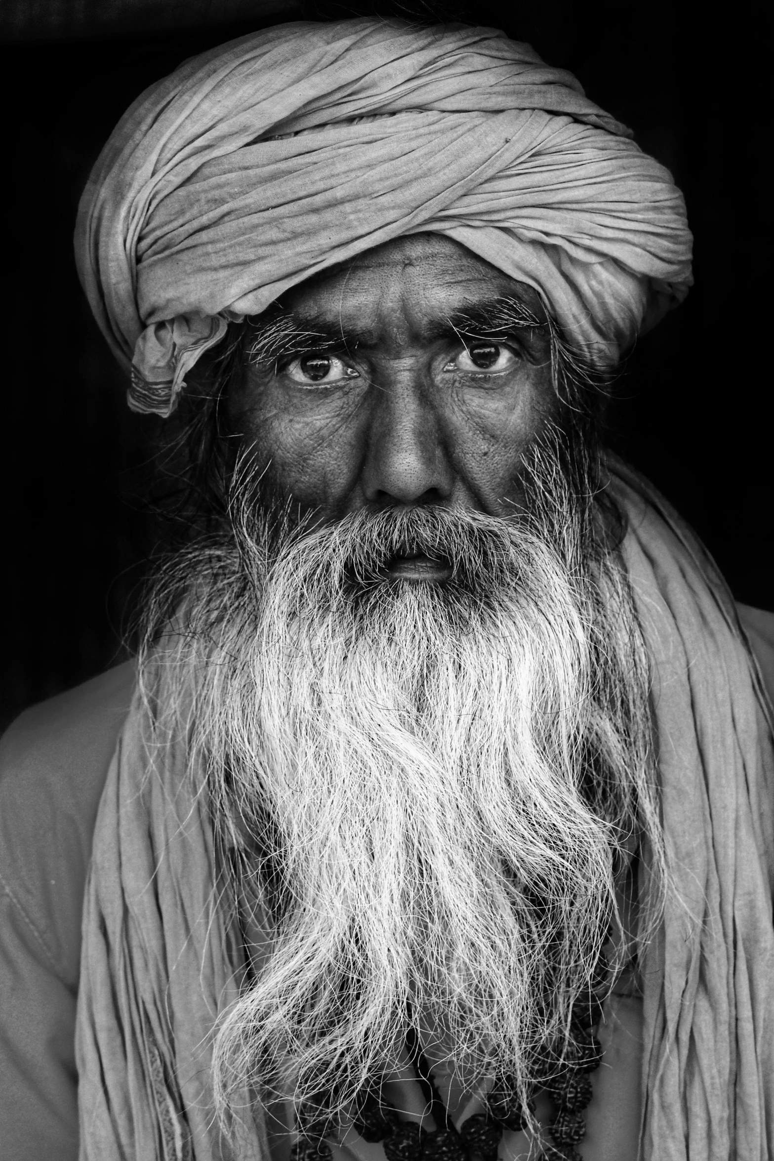 a man with a long beard wearing a turban, a black and white photo, inspired by Steve McCurry, wise old indian guru, a photo of a man, portrait of a sharp eyed, portrait of a red sorcerer