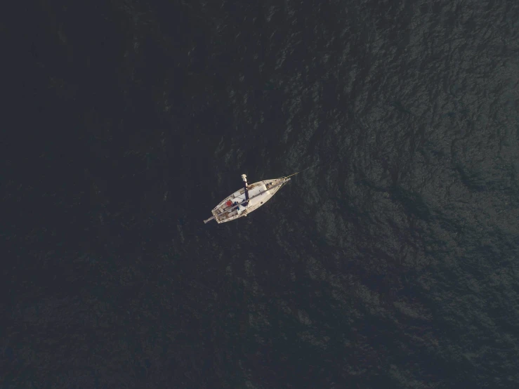 a small boat in the middle of a large body of water, an album cover, pexels contest winner, satellite view, sailboat, dark dingy, movie still 8 k