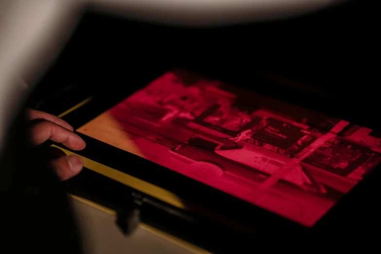 a close up of a person holding a tablet, a hologram, unsplash, video art, red ink, collodion photography, cinematic counter light, lithography