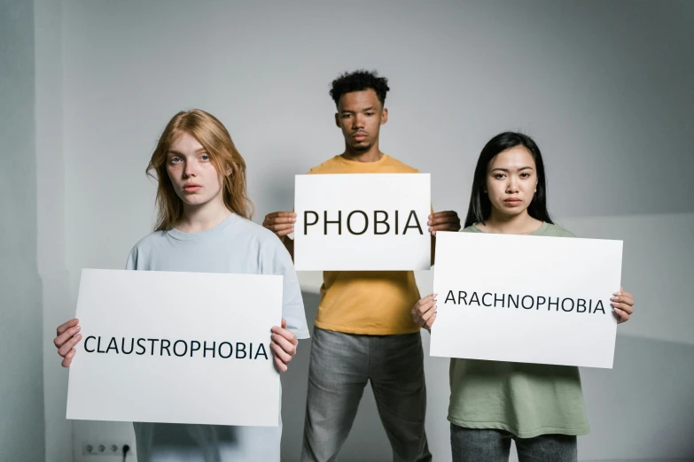 a group of people holding signs that say phobia, by Arabella Rankin, trending on unsplash, antipodeans, plain background, albino, worried, atmospheric phenomenon