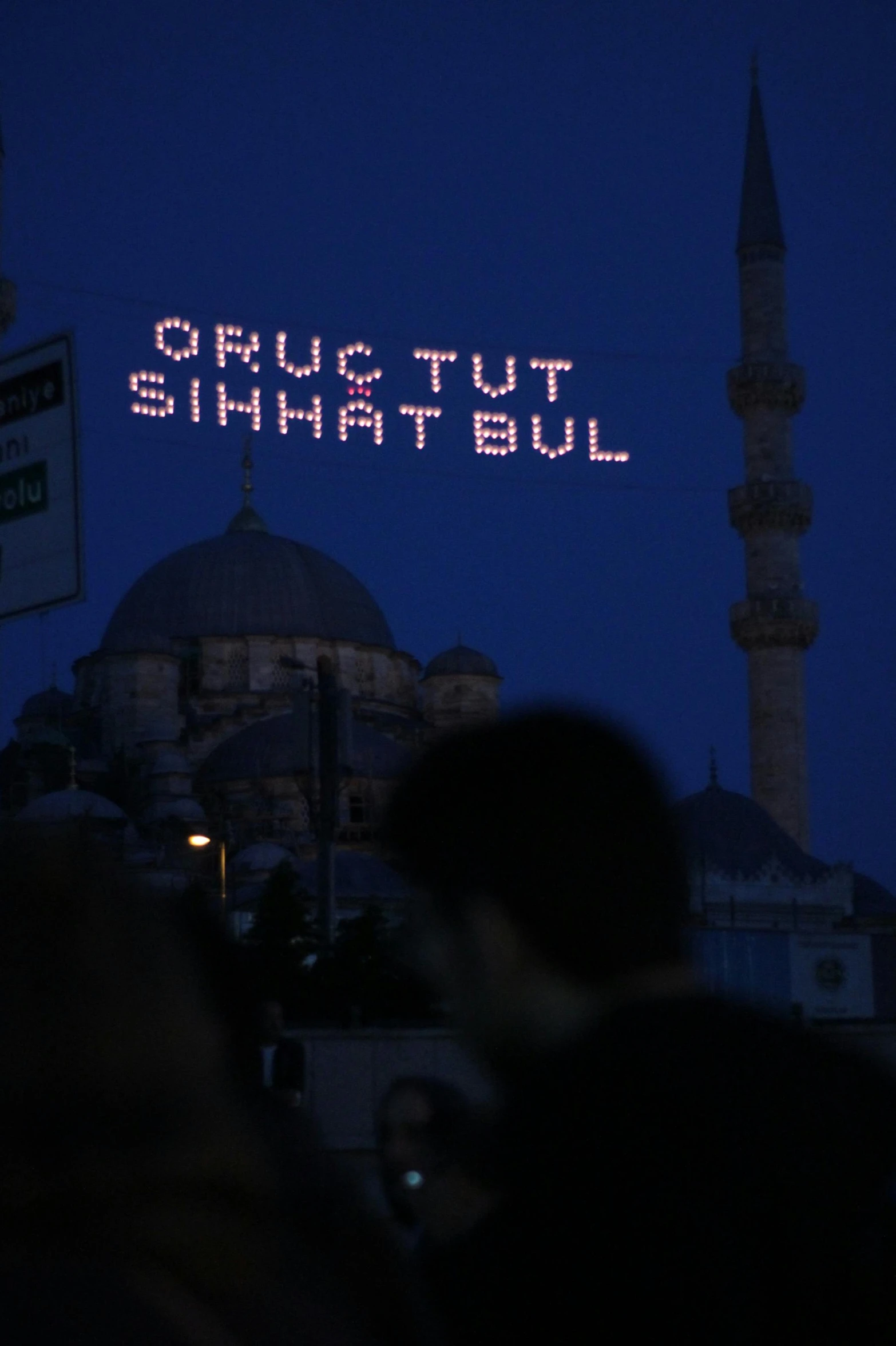 people standing in front of a building with a message on it, by Muggur, hurufiyya, emitting light ornaments, streetlights, dug stanat, ap news photograph