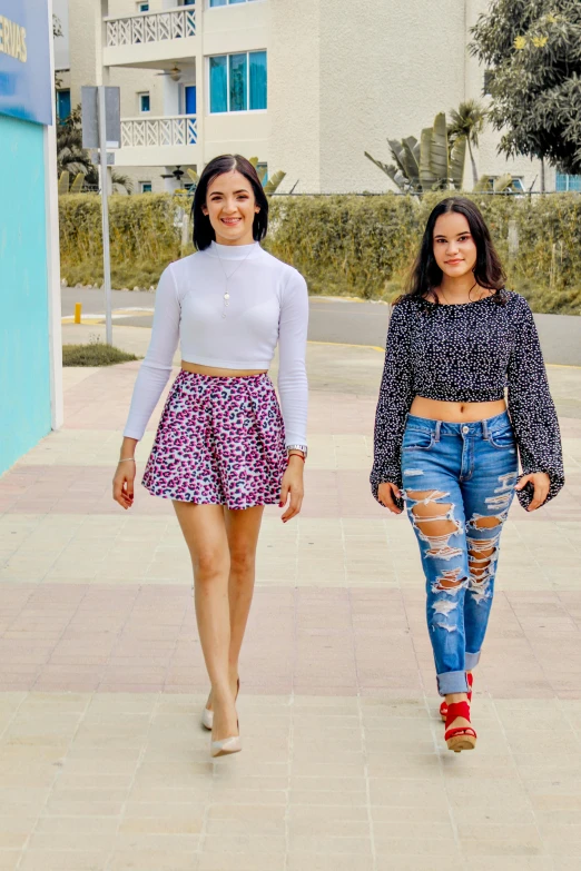 two women walking down a sidewalk next to a building, by Robbie Trevino, instagram, happening, wearing a cropped top, ameera al taweel, 15081959 21121991 01012000 4k, teenagers