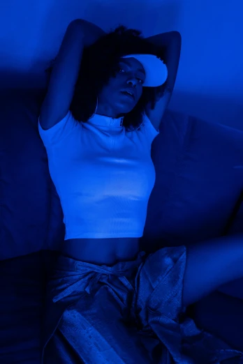 a woman laying on a couch with her eyes closed, an album cover, trending on reddit, dramatic white and blue lighting, uv blacklight, exposed midriff, standing in a dimly lit room