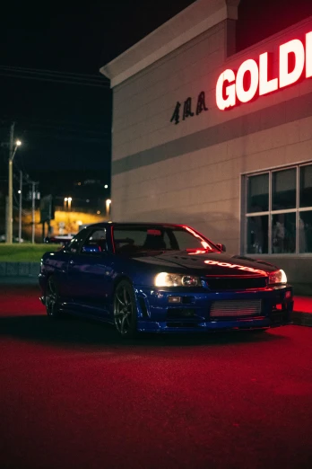 a blue car parked in front of a building, featured on reddit, shining gold and black and red, gtr xu1, good lighted photo, 90's color photo