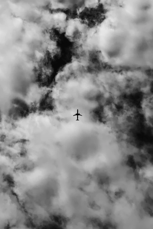 a black and white photo of an airplane in the sky, by Peter Churcher, pexels contest winner, ✨🕌🌙, liminal space aesthetic, toxic clouds, head straight down