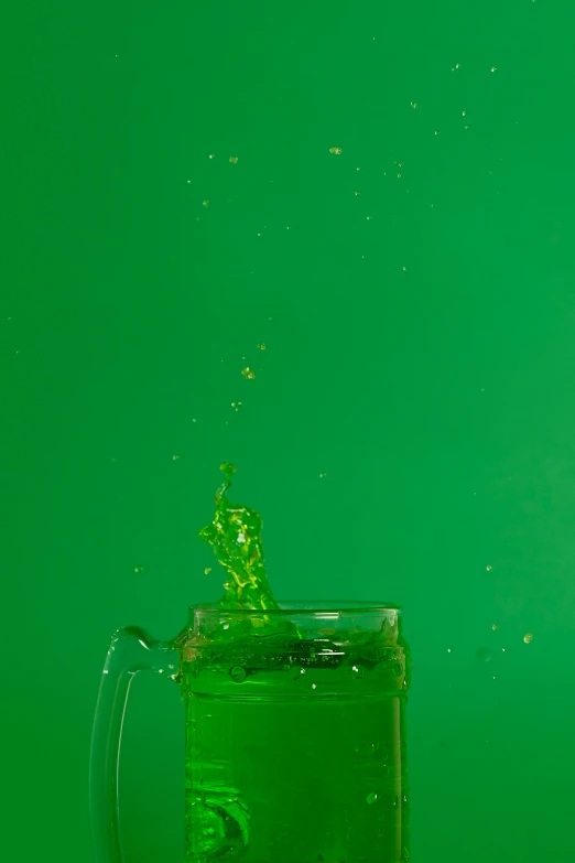 a glass filled with green liquid sitting on top of a table, a picture, pexels, conceptual art, big splash, made of drink, leaping, photobash