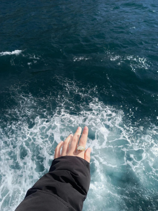 a person standing on top of a boat in the ocean, point finger with ring on it, last photo ever taken, swirling, trending on vsco