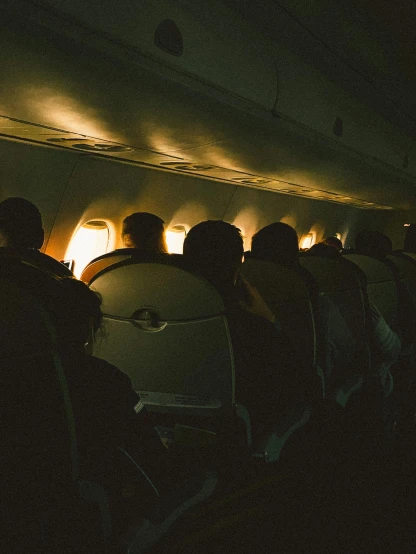 a group of people sitting inside of an airplane, inspired by Elsa Bleda, happening, night light, instagram post, somber lighting, holy glow