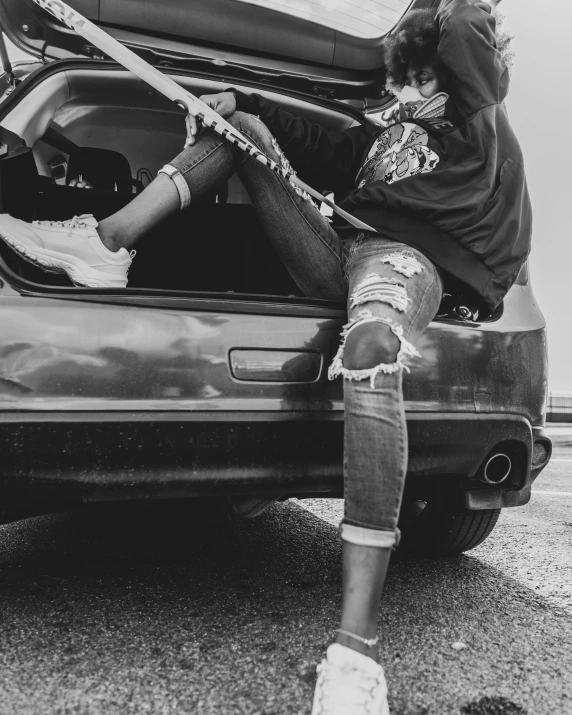 a woman sitting in the trunk of a car, a black and white photo, pexels contest winner, auto-destructive art, trippie redd, ripped jeans, holding a wrench, female streetwear blogger