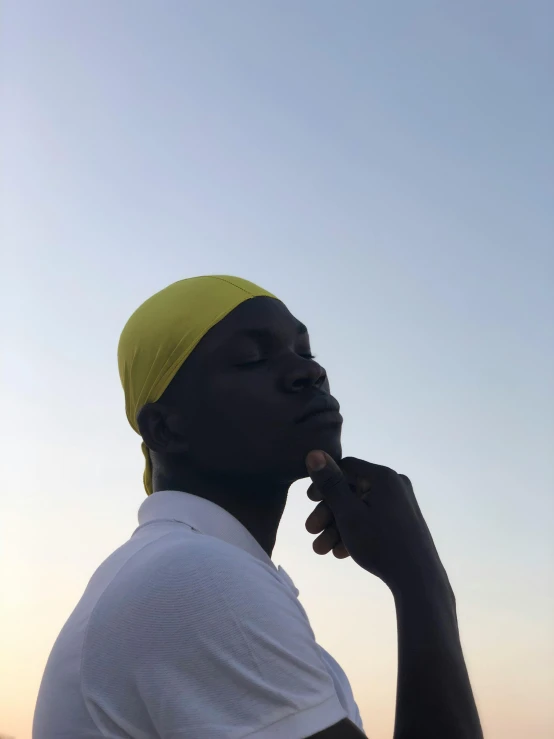 a man in a white shirt and a yellow hat, inspired by Ras Akyem, trending on unsplash, non binary model, ☁🌪🌙👩🏾, profile picture, adut akech