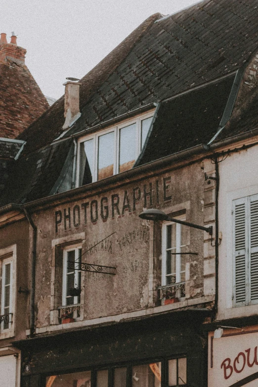 a couple of buildings that are next to each other, a picture, by Raphaël Collin, trending on pexels, post-impressionism, old signs, taupe, camera photo, low quality photo